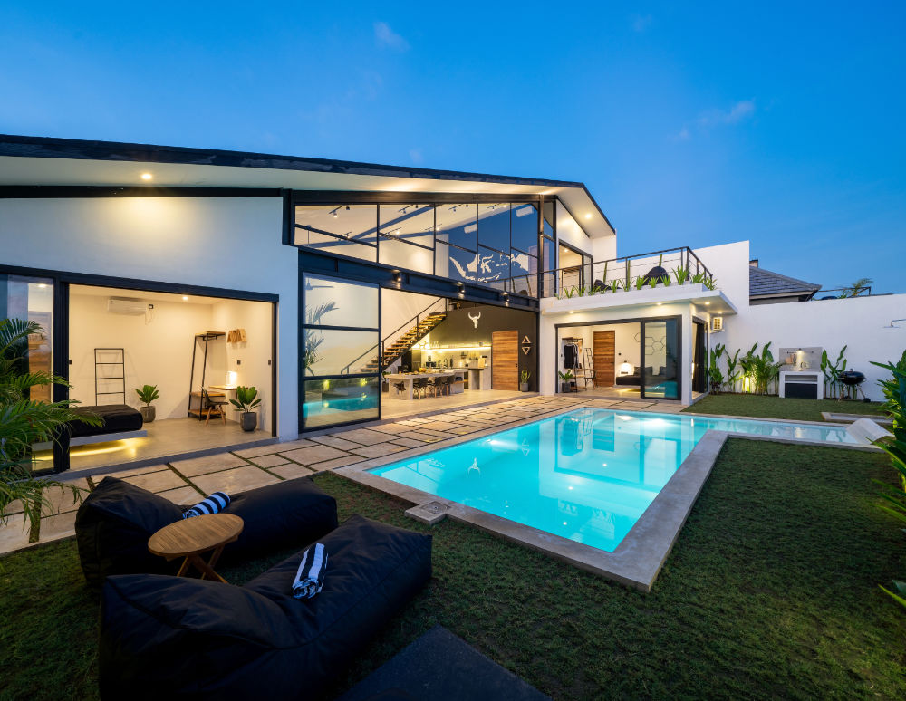 Luxury home with large glass windows view from backyard with pool.